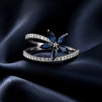 MUHUANG sapphire and diamond floral ring displayed on dark blue satin fabric