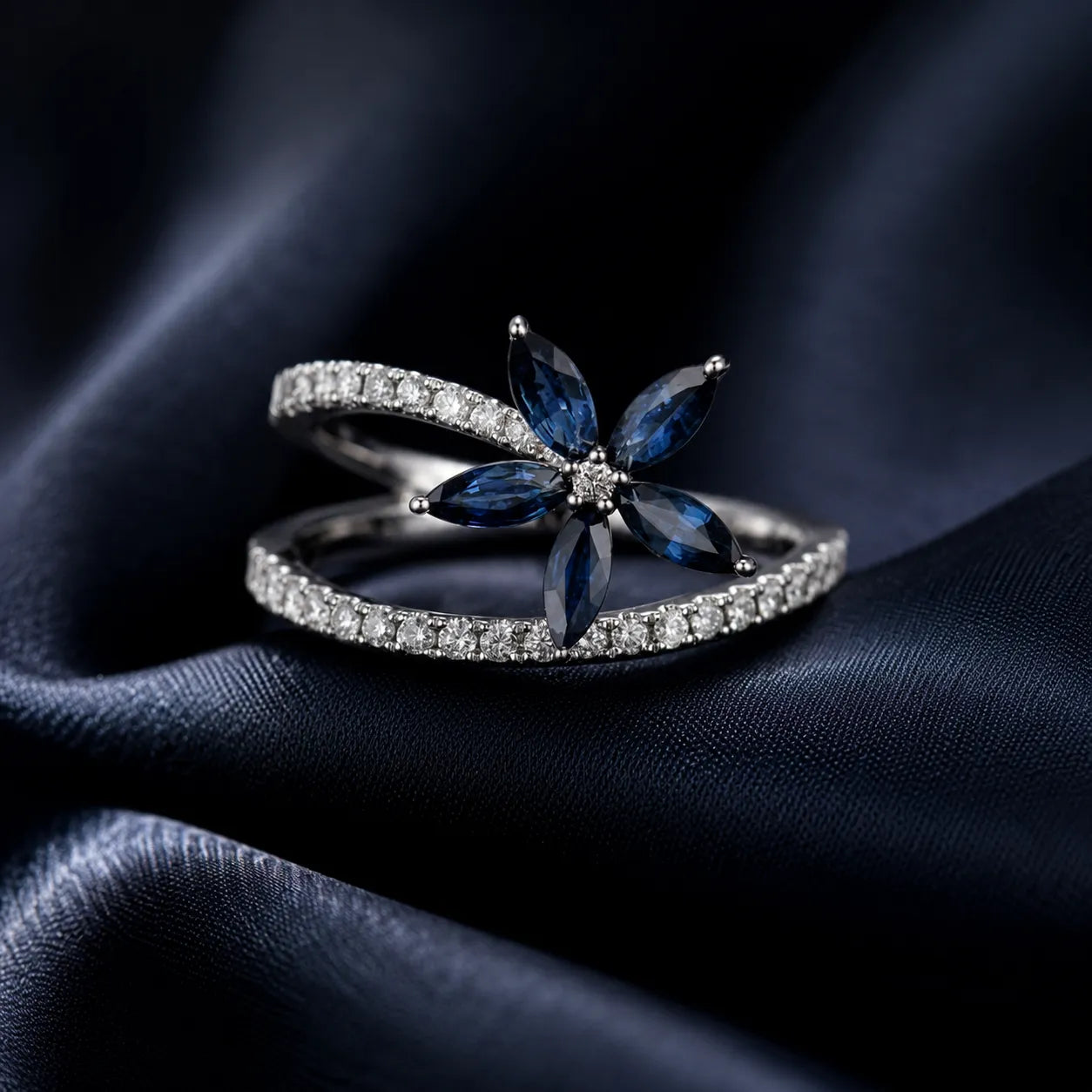 MUHUANG sapphire and diamond floral ring displayed on dark blue satin fabric