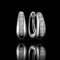 MUHUANG white gold diamond huggie hoop earrings on black reflective background