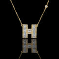 MUHUANG gold "H" pendant necklace with baguette and round diamonds, close-up on black background emphasizing sparkle and premium design.
