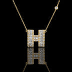 MUHUANG gold "H" pendant necklace with baguette and round diamonds, close-up on black background emphasizing sparkle and premium design.