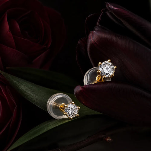 MUHUANG yellow gold diamond stud earrings styled with dark burgundy flowers
