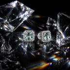 MUHUANG cushion-cut light blue gemstone earrings surrounded by crystal fragments on black reflective surface, showcasing sparkle and premium design.
