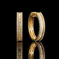 MUHUANG yellow gold baguette diamond hoop earrings on black reflective background