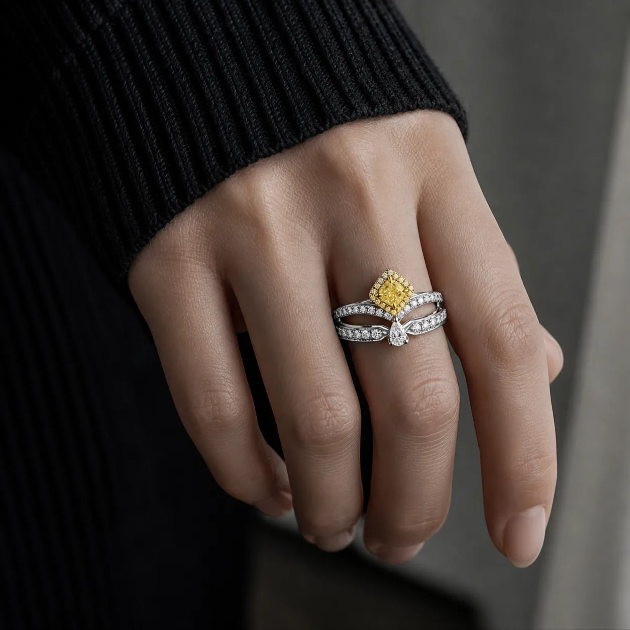 Close-up of hand wearing 18K yellow and white gold yellow diamond ring, highlighting sparkling cushion-cut yellow center