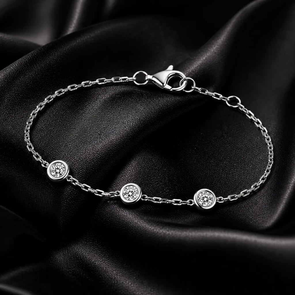 Close-up of three-diamond white gold bracelet on black satin, highlighting chain and clasp details