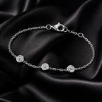 Close-up of three-diamond white gold bracelet on black satin, highlighting chain and clasp details