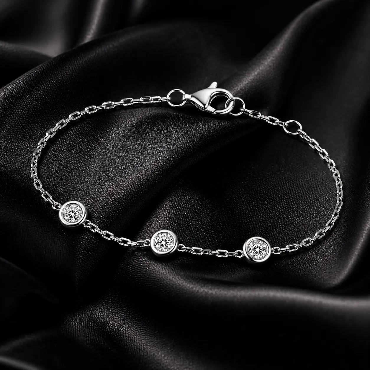 Close-up of three-diamond white gold bracelet on black satin, highlighting chain and clasp details