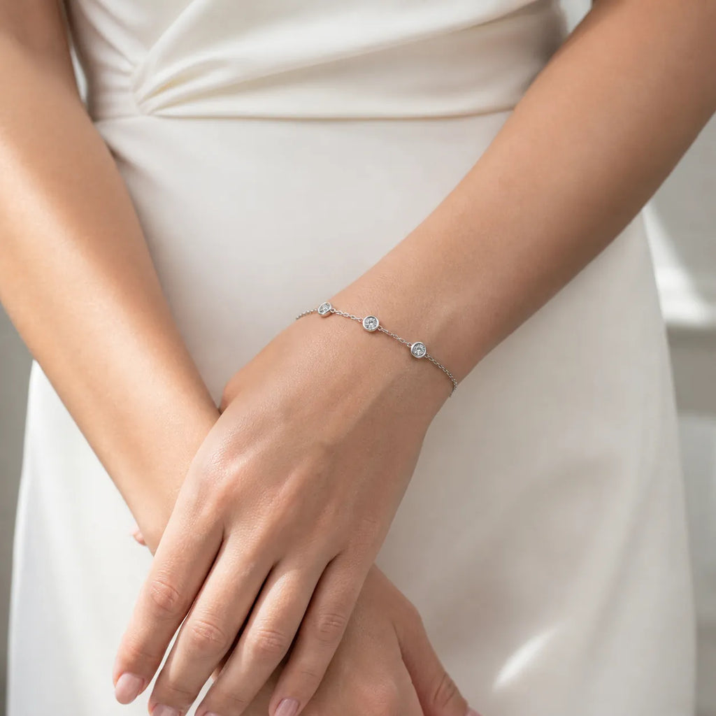 Diamond bracelet on wrist, photographed with white dress, showcasing sparkling bezel-set stones