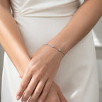Diamond bracelet on wrist, photographed with white dress, showcasing sparkling bezel-set stones