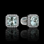 MUHUANG square-cut light blue gemstone stud earrings with diamond halo on reflective black surface, highlighting elegance and brilliance.